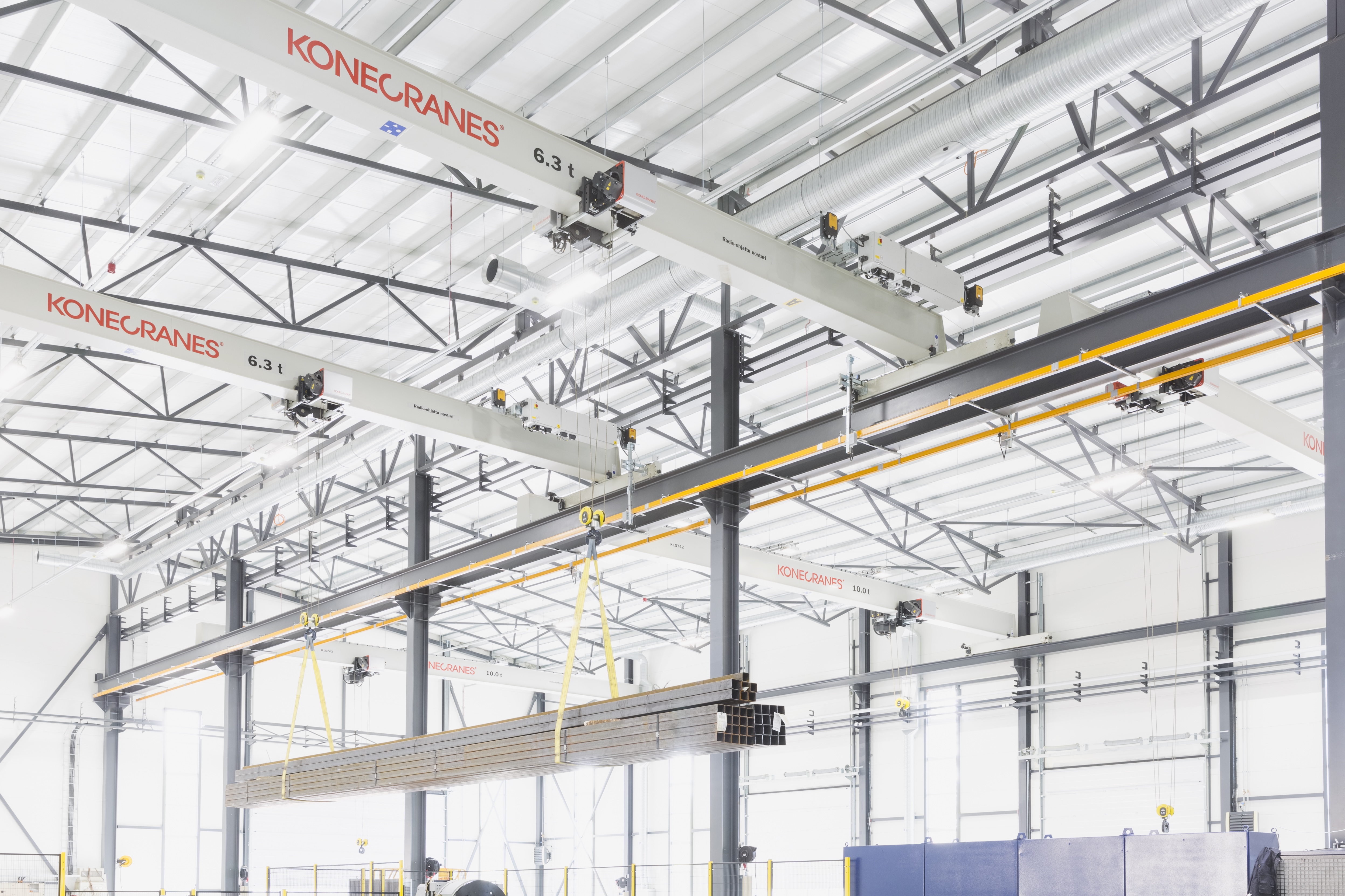Der Konecranes CXT Neo Brückenkran in einer Fertigungshalle, während eine Last gehoben wird.