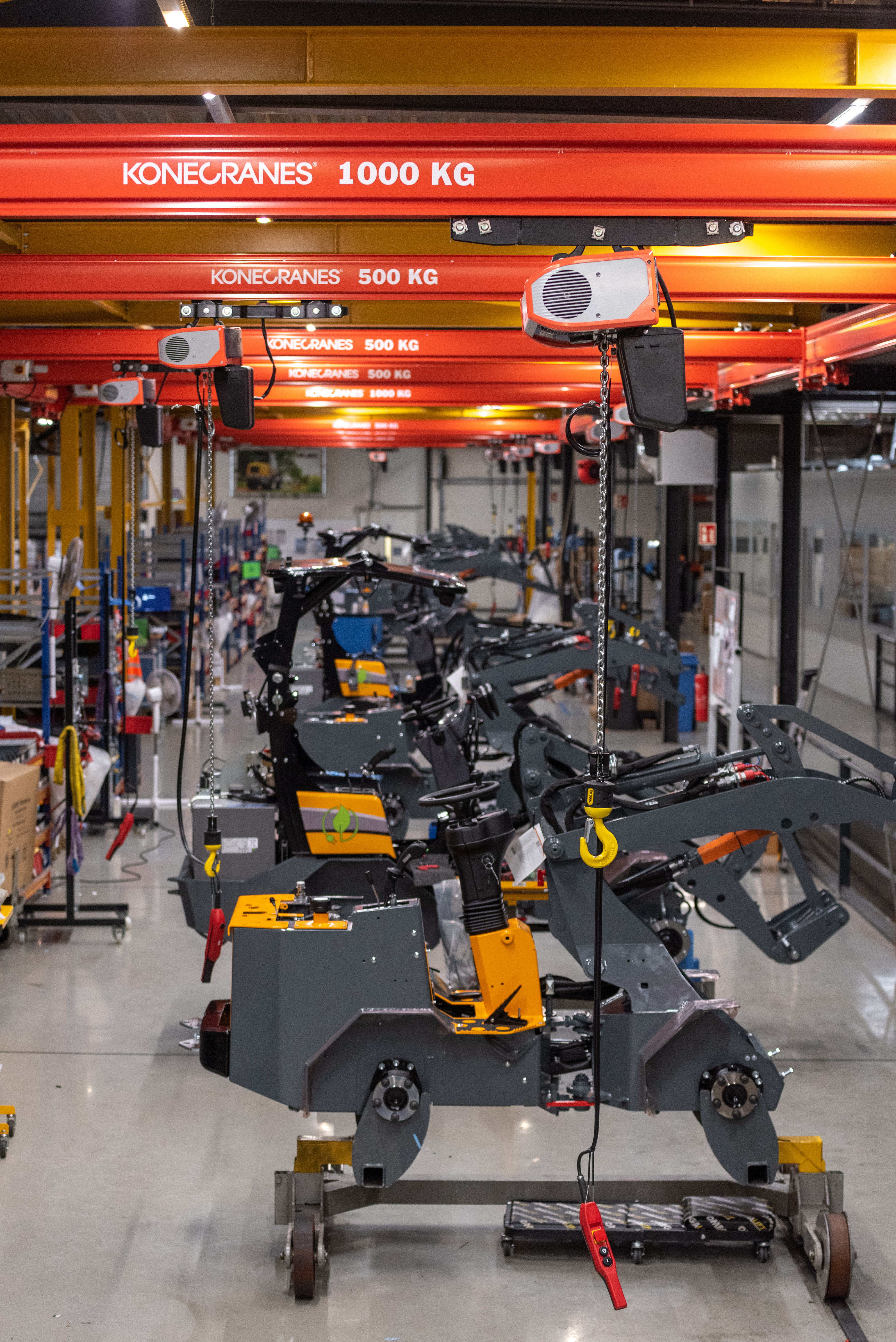 Konecranes KBK Stahl Arbeitsplatzkran mit dem Konecranes C-Serie Elektrokettenzug an einer Arbeitsstation mit dem Fahrgestell eines Radladers.